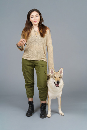 De cuerpo entero de una maestra de pie junto a su perro y mirando a la cámara