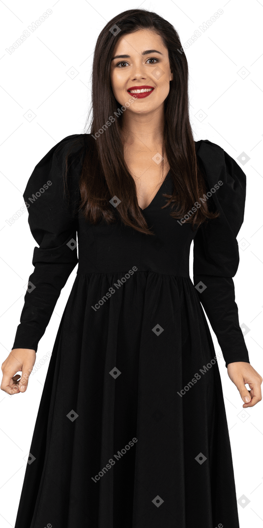 Вид спереди улыбающейся молодой леди в черном платье, стоящей на месте