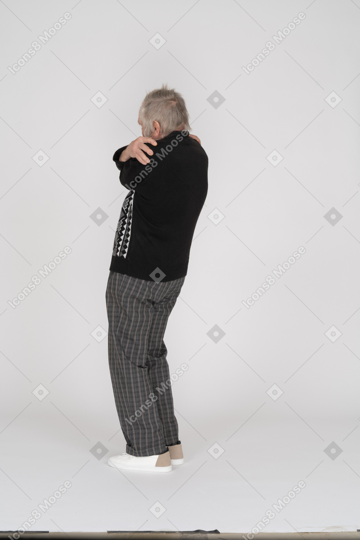Back view of an elderly man hugging himself