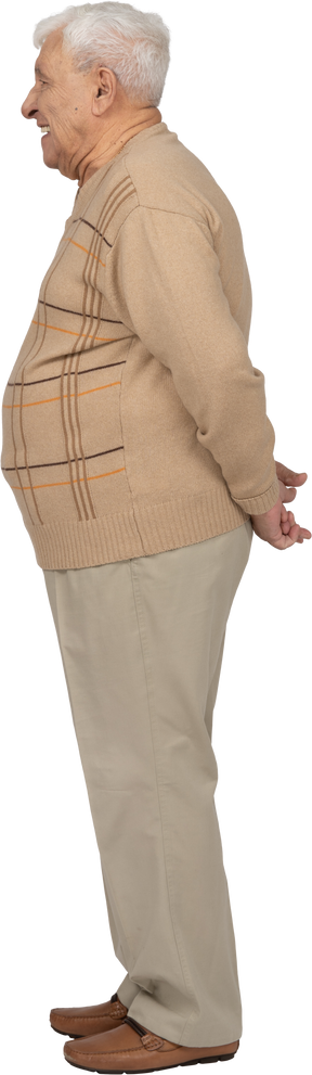 Vue latérale d'un vieil homme en vêtements décontractés debout avec les mains derrière le dos