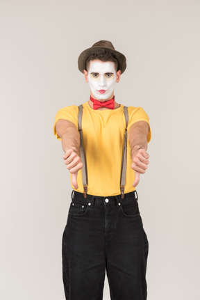 Sad looking male clown showing thumbs down with both hands