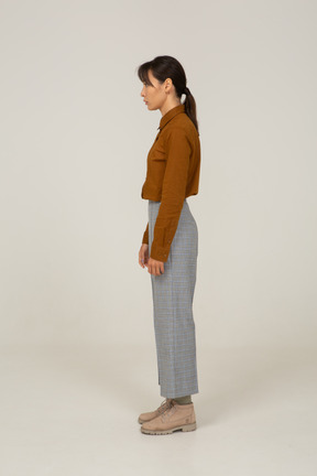 Side view of a young asian female in breeches and blouse standing still