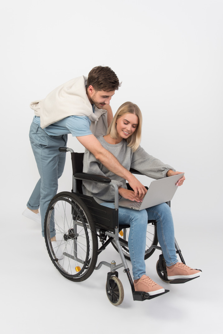 Handsome guy and a girl in wheelchair using notebook
