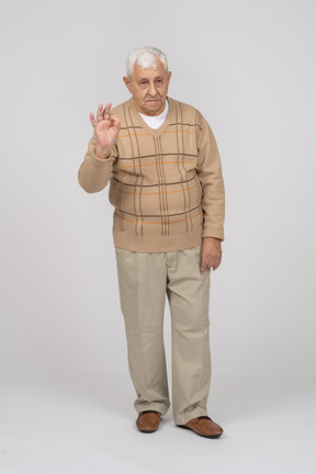 Front view of an old man in casual clothes showing ok sign