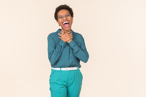 Black woman with a short haircut, wearing all blue, standing against a plain pastel background, looking emotional