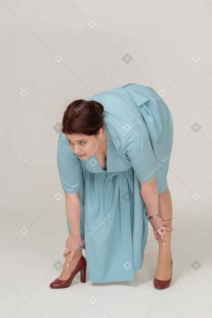 一个穿着蓝色连衣裙的女人弯下腰的前视图