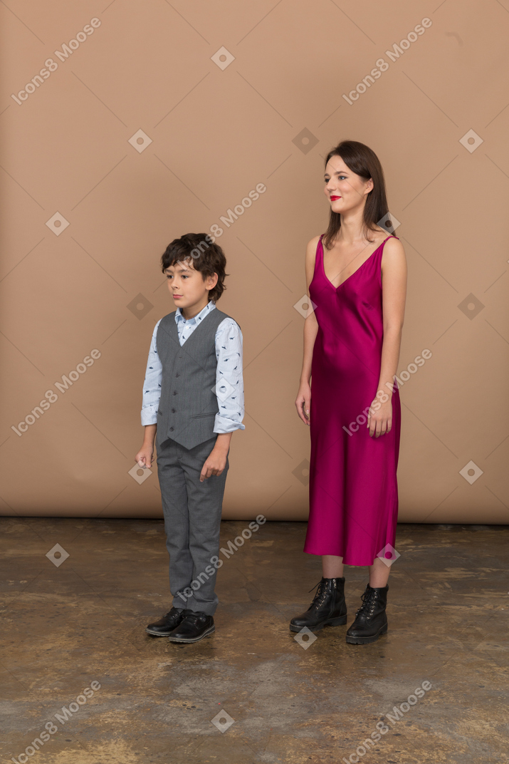Mulher de vestido vermelho e garotinho parado em seu perfil
