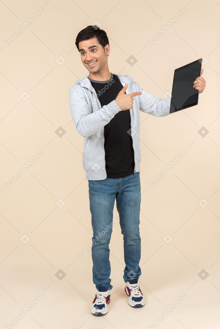 Junger kaukasischer mann, der auf eine digitale tablette zeigt, die er hält