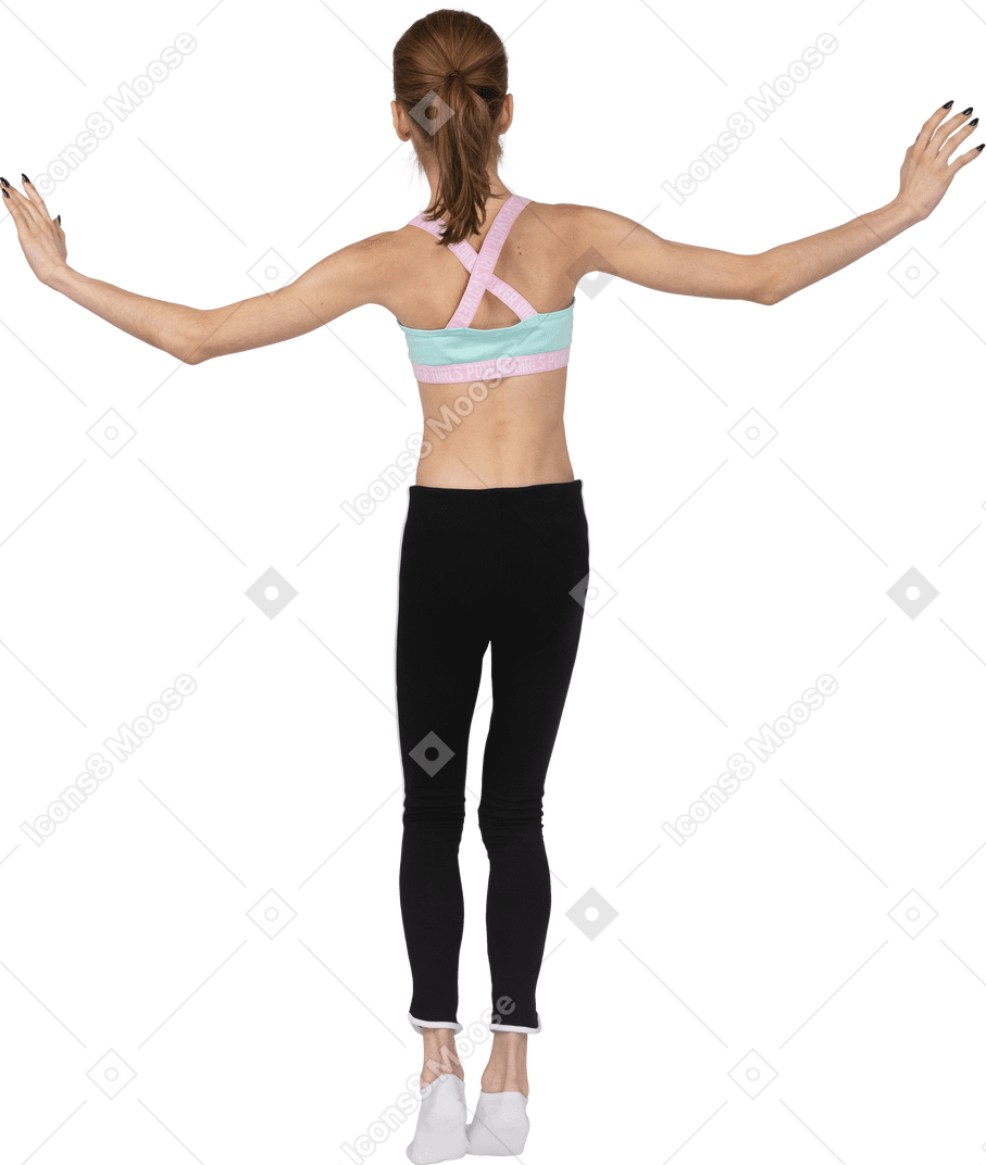 Vista posteriore di una ragazza adolescente in abiti sportivi in equilibrio sulla punta dei piedi mentre alza le mani