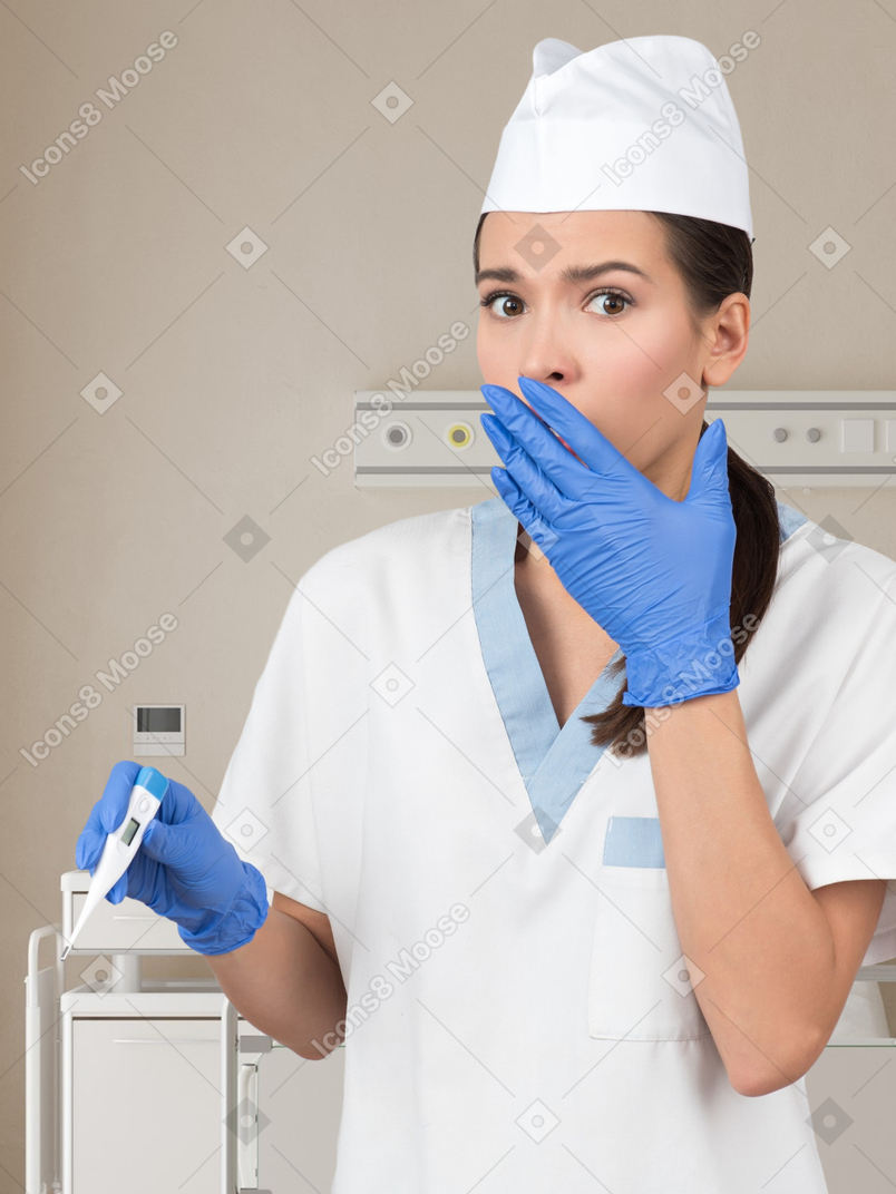 Shocked nurse holding a thermometer