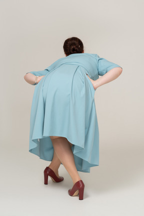 Вид сзади женщины в синем платье наклоняется