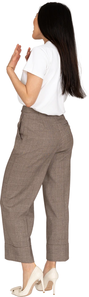 Three-quarter back view of a shouting gesticulating young lady in breeches and t-shirt
