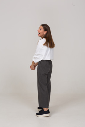Vista posterior de tres cuartos de una joven riendo en ropa de oficina