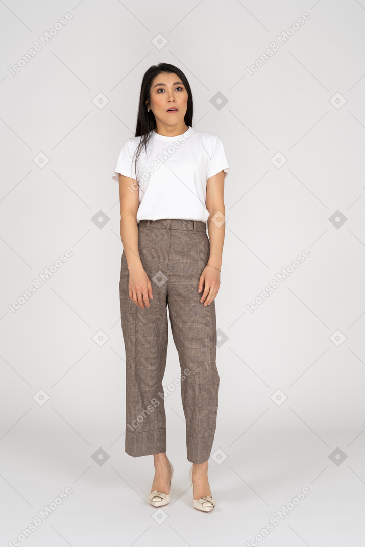 Front view of a surprised young lady in breeches and t-shirt standing looking aside