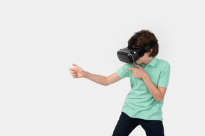 Niño con casco de realidad virtual sosteniendo un arma invisible