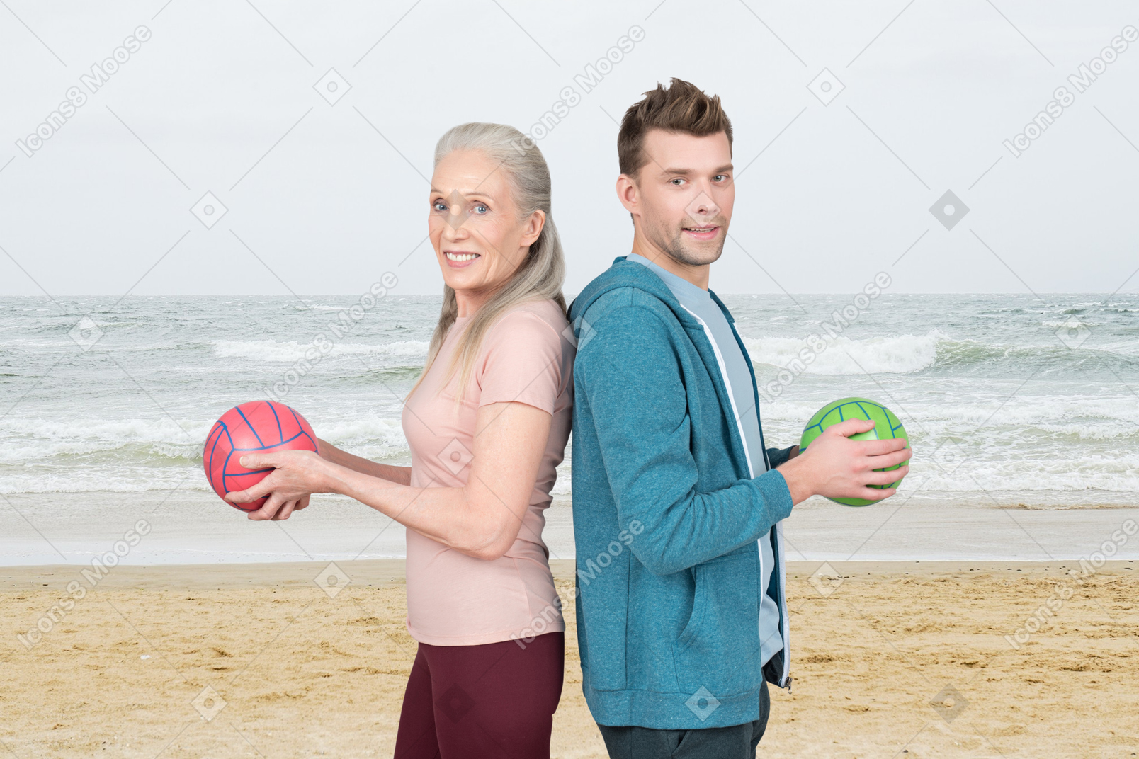 A man and a woman holding volleyball balls on the beach