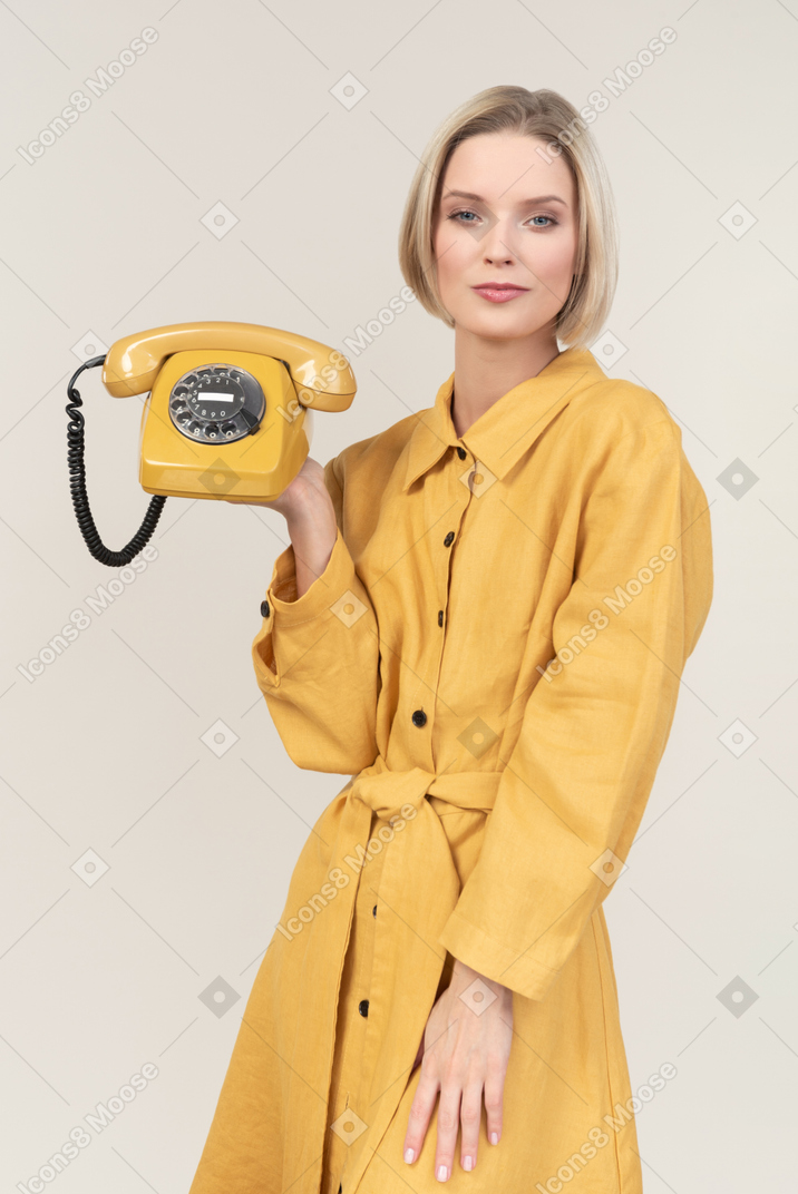 Young woman holding old yellow rotary phone