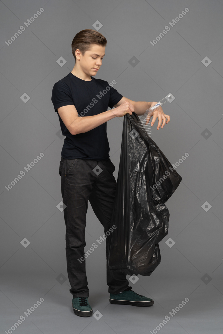 Un joven llenando una bolsa de basura