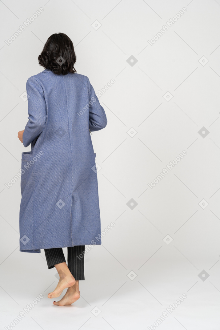 Vista traseira da mulher de casaco com os pés descalços