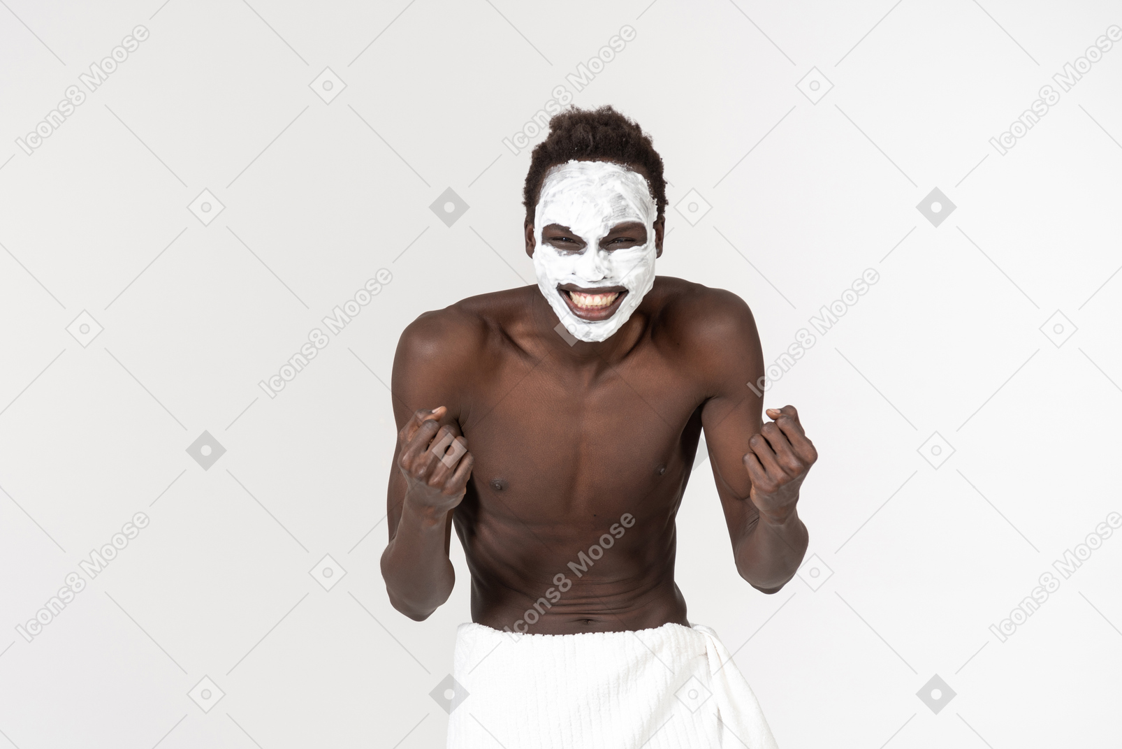 A young black man with a white bath towel around his waist going about his facial care