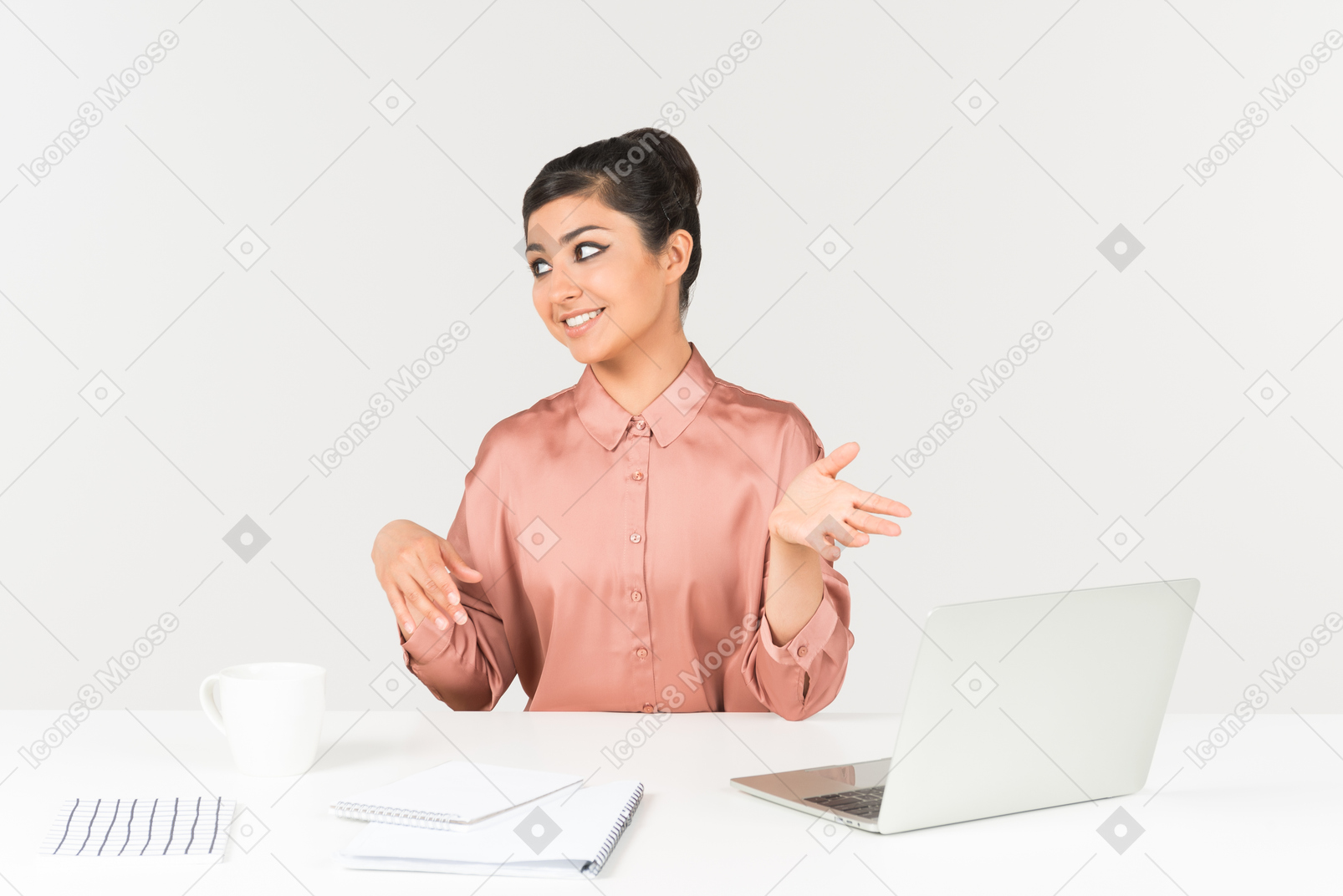 Young indian woman sitting at the office desk and pointing with both hands