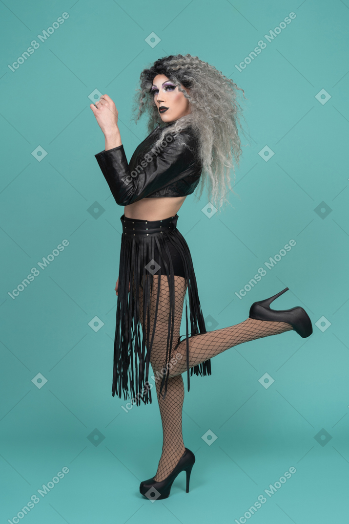 Drag queen in leather jacket raising arm and leg