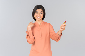 Femme indienne en haut orange portant du rouge à lèvres et tenant un