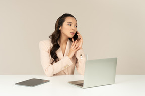 Asiatischer weiblicher büroangestellter, der sorgfältig auf telefonanruf hört