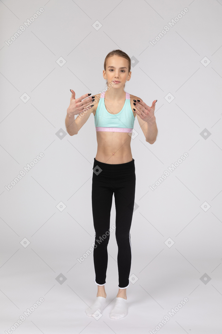 しゃがんで腰に手を置くスポーツウェアの10代の少女の側面図