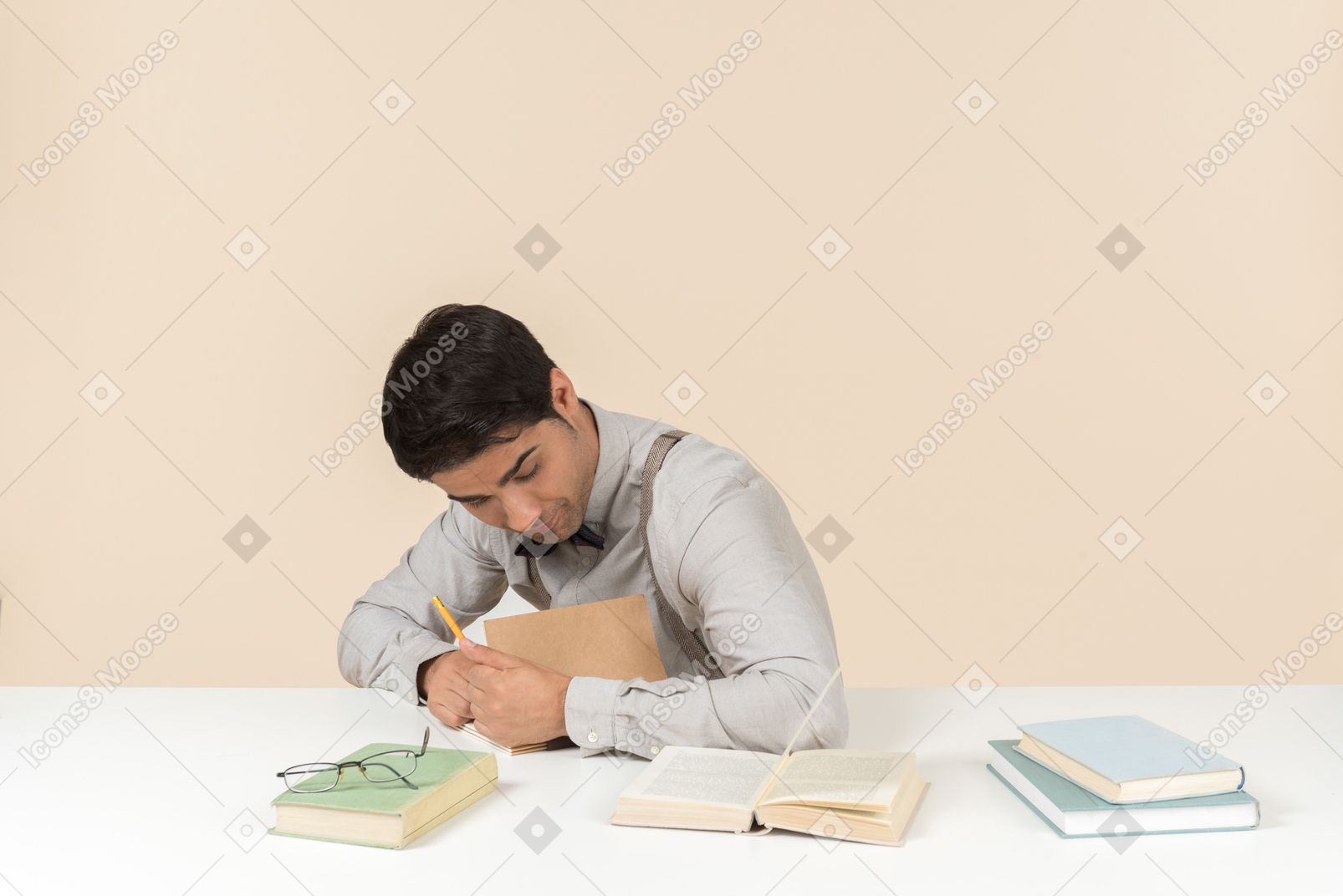 テーブルに座って、本に何かを書く若い大人の学生