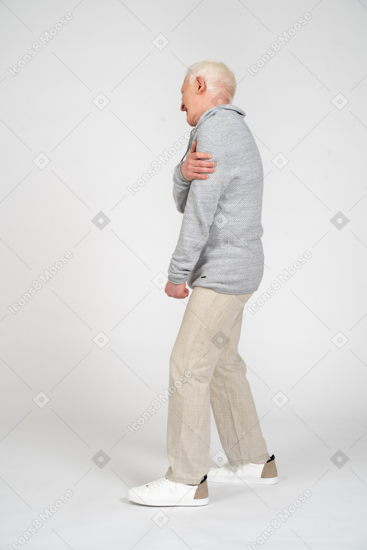 Vista lateral de um homem de pé e segurando seu braço
