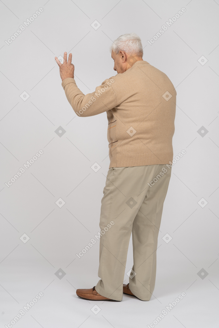 Vista traseira de um velho em roupas casuais, mostrando sinal de ok