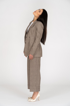 頭を傾けながら見上げる茶色のビジネススーツの若い女性の側面図