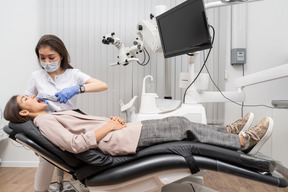 Comprimento total de uma dentista extraindo o dente de seu paciente em um armário de hospital