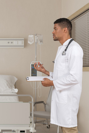 A man in a white lab coat standing next to a hospital bed