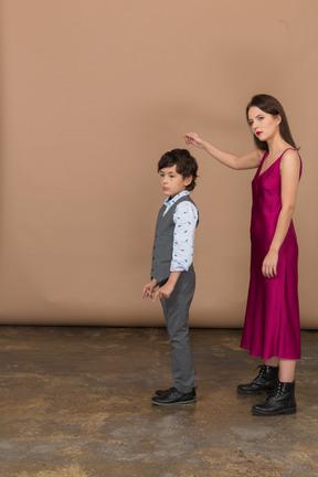 Young woman in red dress and boy standing still