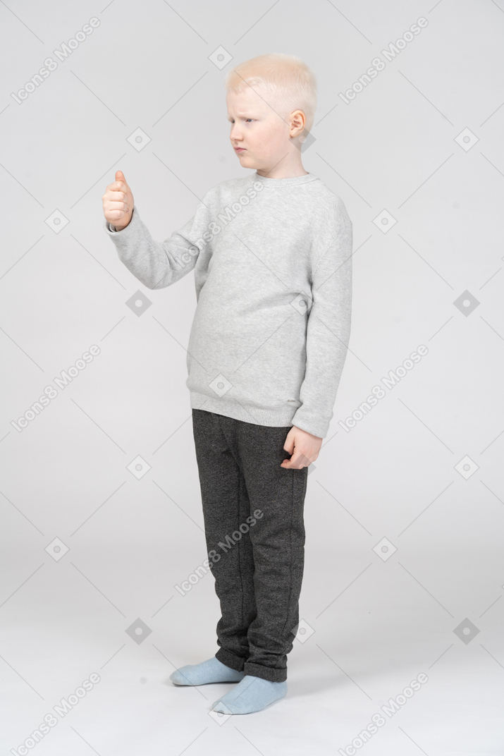 Сварливый маленький мальчик стоит с поднятым кулаком