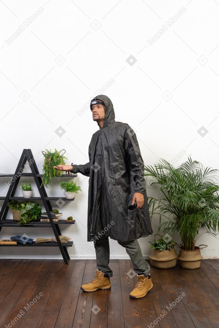 Mann im regenmantel fängt regentropfen auf der handfläche