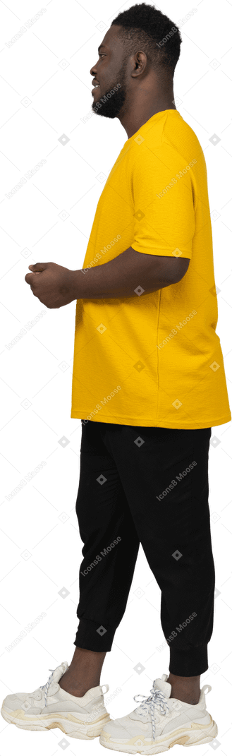 노란색 티셔츠를 입은 어두운 피부의 젊은 남자가 가만히 서 있는 모습