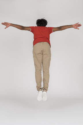 Young man jumping forward with spread arms