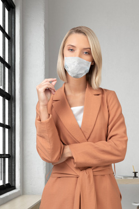 A woman wearing a face mask standing in front of a window