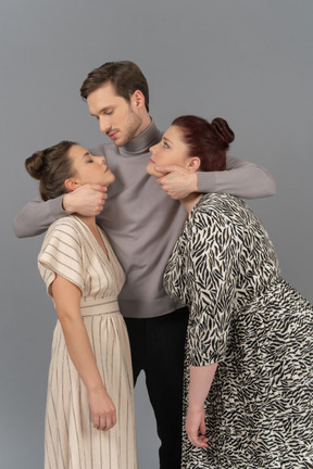 Young man embracing two women by the necks