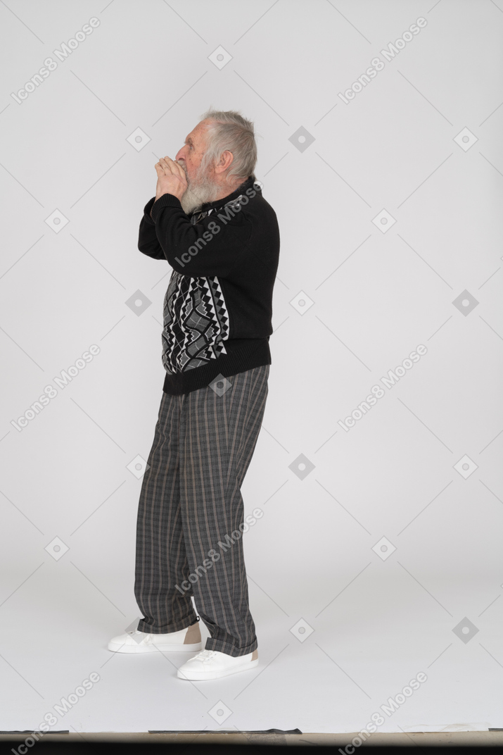 Vista lateral del anciano gritando con las manos alrededor de la boca