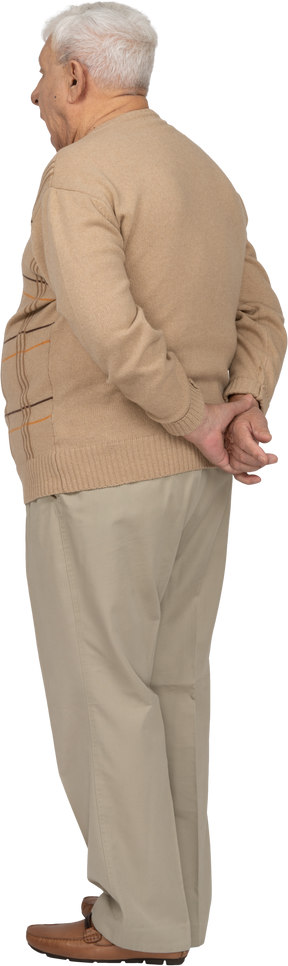 Vista lateral de um velho em roupas casuais em pé com as mãos atrás das costas
