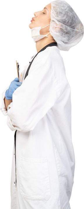 Side view of a sleepy young female doctor holding pencil and tablet