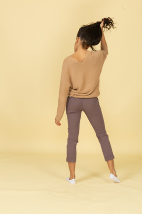 Back view of a dark-skinned young lady grabbing her hair