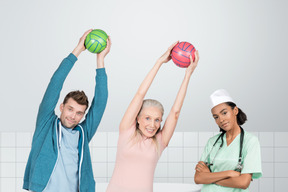 A nurse and two people exercising with balls