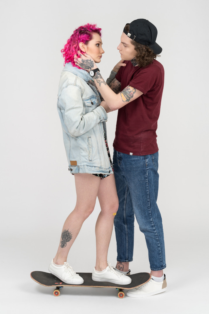 Tattooed young man is about to kiss his pink haired girlfriend