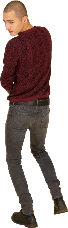 Vista posteriore di un giovane uomo in pullover rosso che osserva da parte