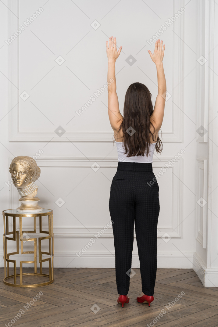 Back view of young woman raising hands